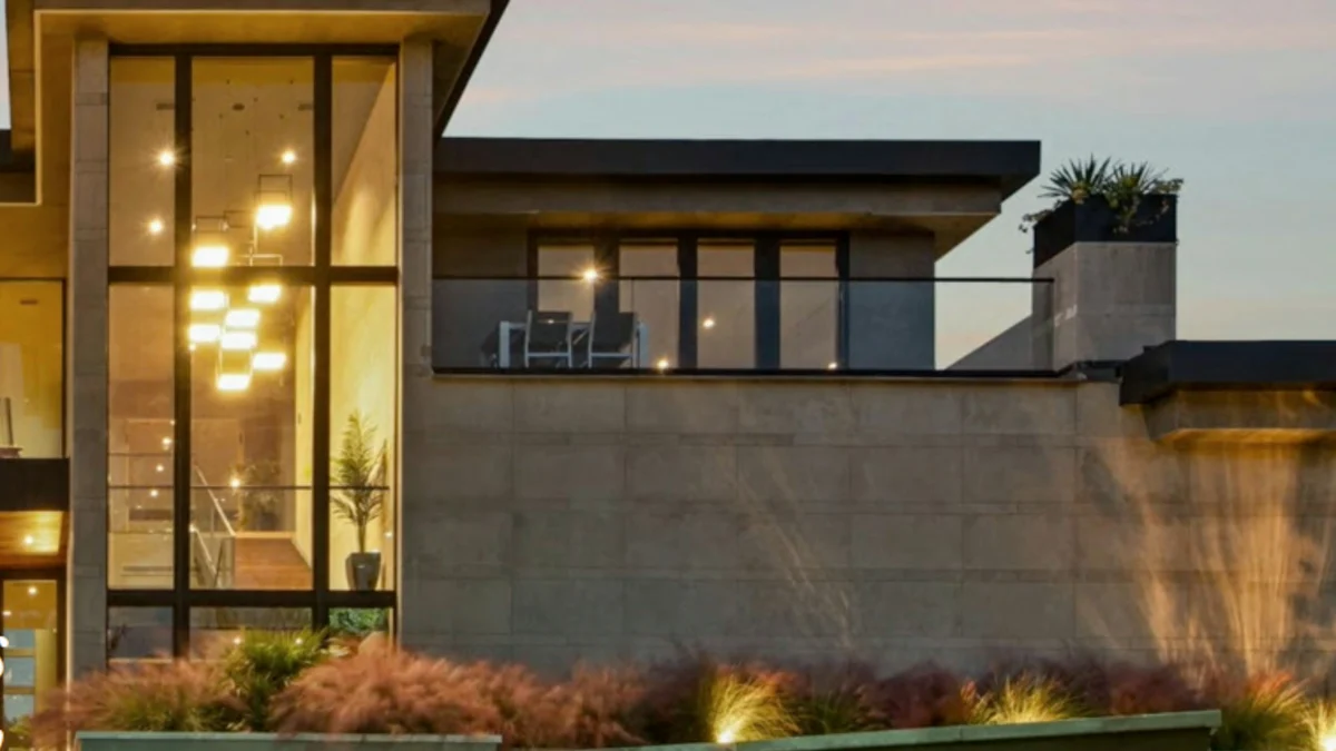 Modern luxury residence set into its lot, seen from the garden side at dusk